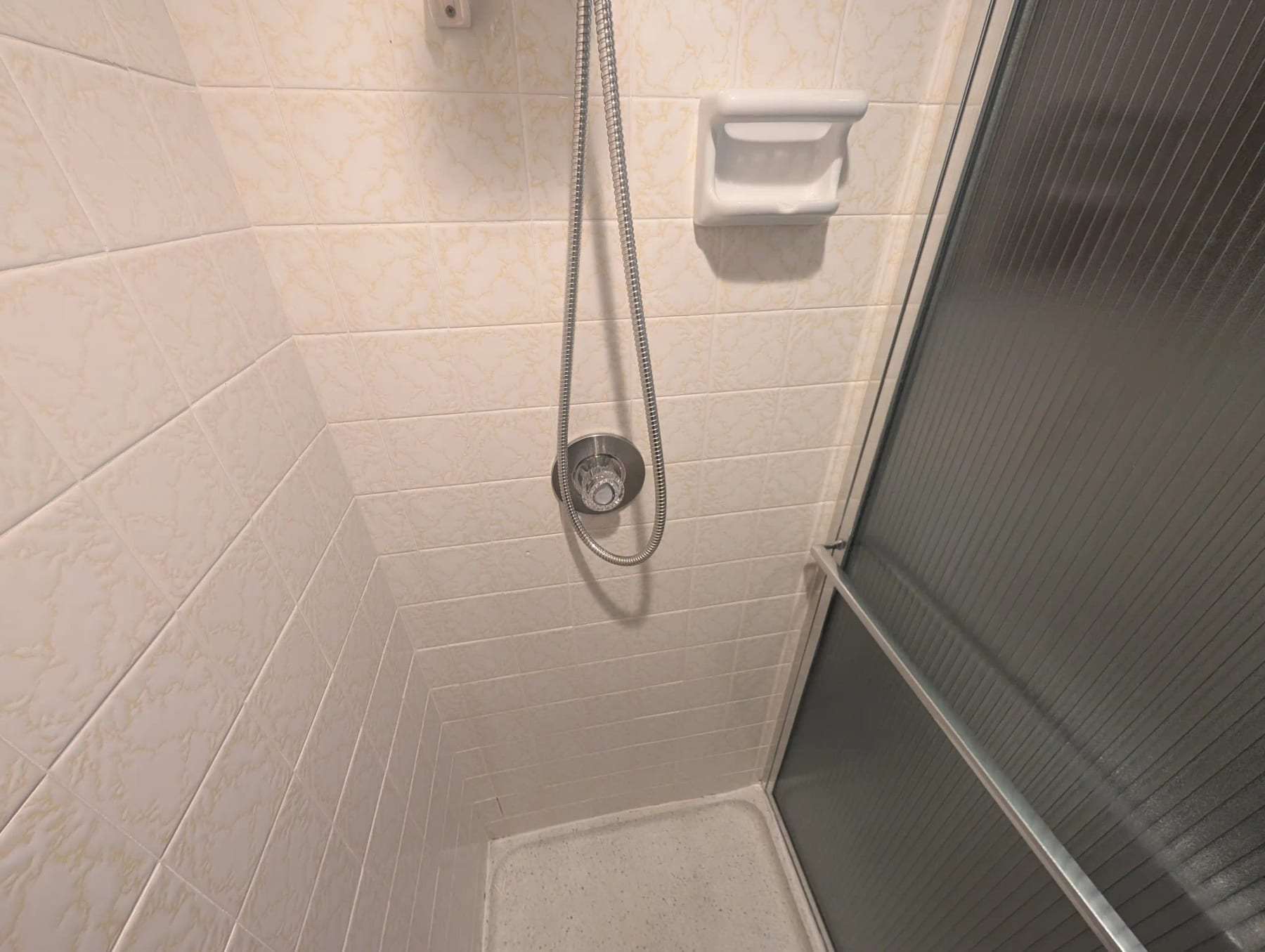Shower stall with a handheld shower head and a soap dish